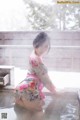 A woman in a pink kimono sitting in a pool of water.