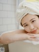 A young girl with a towel wrapped around her head in a bathtub.