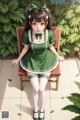 A girl in a green dress sitting on a chair.