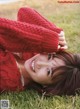 A woman laying on the grass wearing a red sweater.