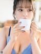 A woman in a blue lingerie holding a white cup.