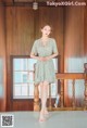 A woman standing in front of a wooden wall wearing a dress.