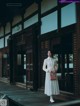 A woman standing on a wooden walkway in front of a building.