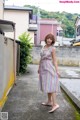 A woman in a striped dress standing on a sidewalk.