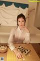 A woman sitting at a table playing a game of checkers.