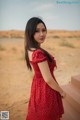 A woman in a red polka dot dress standing in the desert.