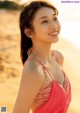 A woman in a red bikini standing on a beach.