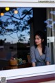 A woman looking out of a window at the sunset.