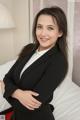 A woman in a black suit standing on a bed.