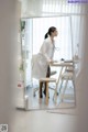 A woman in a white lab coat sitting at a desk.