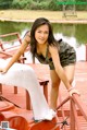 A young woman leaning on a boat on a dock.