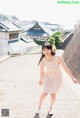 A young girl in a floral dress is walking down a path.