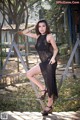 A woman in a black dress posing on a metal fence.