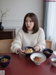 A woman sitting at a table with bowls of food.